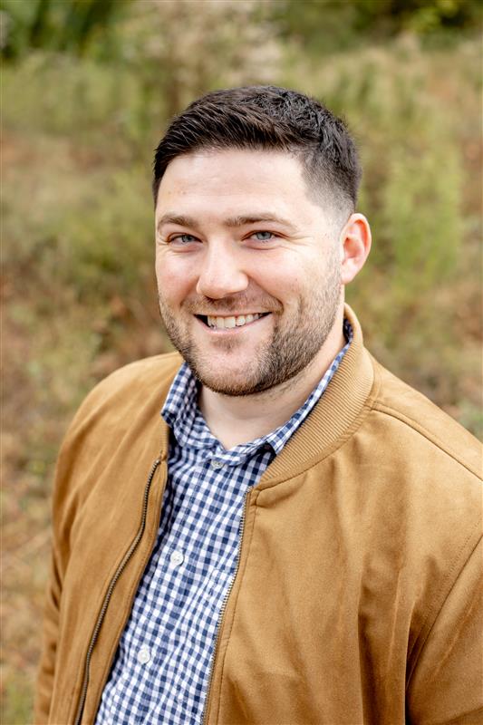 Gordon Culletto smiling in a tan jacket and blue gingham shirt